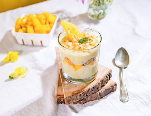 Tropical mango coconut trifle layered with creamy vanilla custard, fresh diced mango, and toasted coconut, served in a glass and topped with mint.