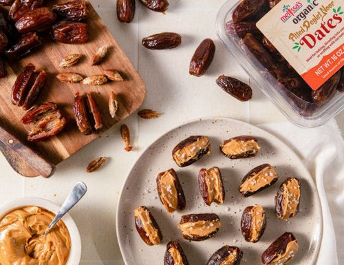 Peanut butter stuffed Deglet Noor dates sprinkled with flaky sea salt on a serving platter.