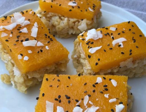 Mango Sticky Rice Crispy Treats featuring a coconut Rice Krispies base topped with fresh Tree Ripened Mango gelatin, finished with toasted coconut flakes and black sesame seeds for a tropical no-bake dessert.