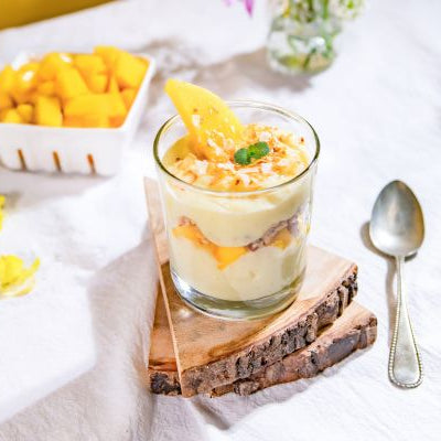 Tropical mango coconut trifle layered with creamy vanilla custard, fresh diced mango, and toasted coconut, served in a glass and topped with mint.