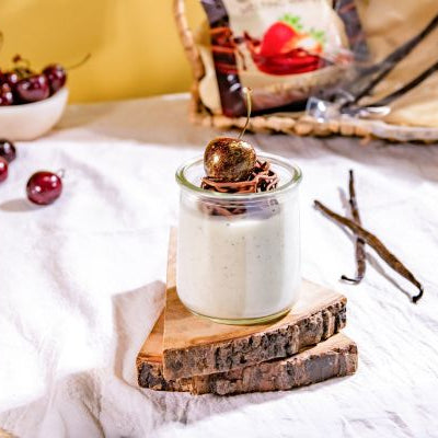 Silky buttermilk panna cotta topped with a delicate chocolate nest and fresh Melissa's Tasmanian cherries, served in a glass jar with vanilla bean accents