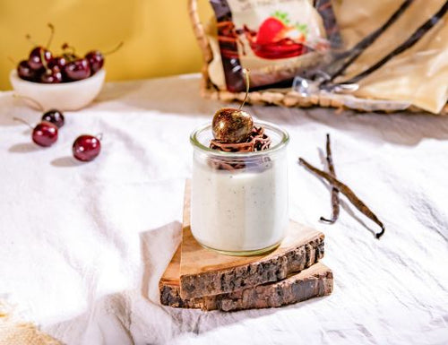 Silky buttermilk panna cotta topped with a delicate chocolate nest and fresh Melissa's Tasmanian cherries, served in a glass jar with vanilla bean accents