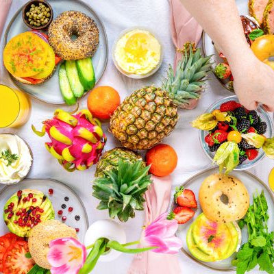 Mother’s Day brunch table with bagels, fruit, spreads, and juice arranged on a pastel setting