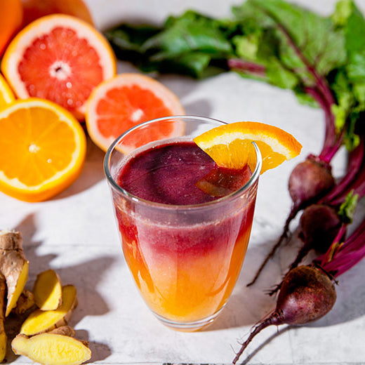 Image of Sunrise Citrus Beet Juice with orange slices and fresh beets in the background