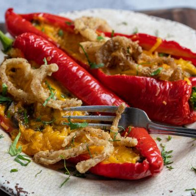 Roasted Italian red peppers stuffed with cheesy rice, mushrooms, and greens, baked until tender and topped with melted cheddar, crispy onions, and parsley.