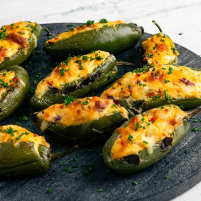 Dutch Potato Jalapeño Poppers filled with creamy mashed potatoes and melted cheese, baked until golden and garnished with fresh herbs on a serving platter