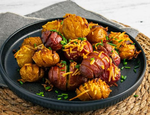 Hot honey buttered Hasselback Dutch potatoes roasted until golden and crispy, topped with melted cheese and fresh chives on a serving plate