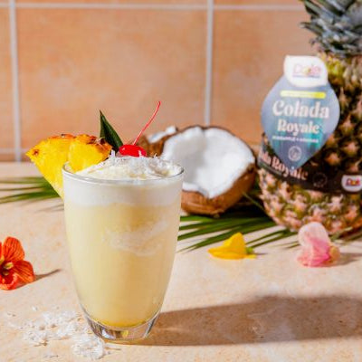 Colada Royale™ Pineapple Piña Colada Agua Fresca with fresh pineapple, coconut, crushed ice, and cherry garnish, served as a refreshing tropical summer beverage.
