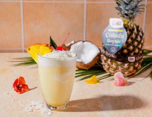 Colada Royale™ Pineapple Piña Colada Agua Fresca with fresh pineapple, coconut, crushed ice, and cherry garnish, served as a refreshing tropical summer beverage.