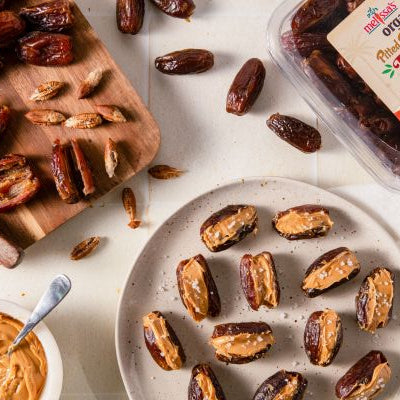 Peanut butter stuffed Deglet Noor dates sprinkled with flaky sea salt on a serving platter.