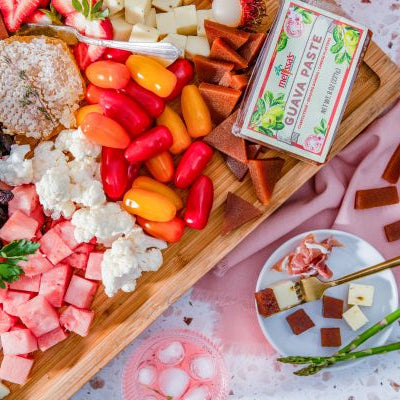 Guava paste grazing board with assorted cheeses, fresh strawberries, colorful peppers, watermelon, cauliflower, and sliced guava paste served with crackers and fruit.