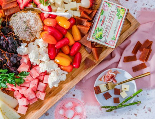 Guava paste grazing board with assorted cheeses, fresh strawberries, colorful peppers, watermelon, cauliflower, and sliced guava paste served with crackers and fruit.
