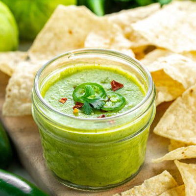 Tomatillo Salsa with chips on a cutting board