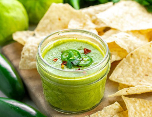 Tomatillo Salsa with chips on a cutting board