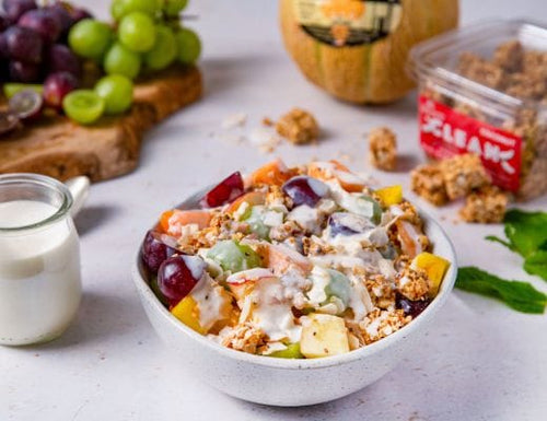 Bowl of Mexican-style Bionicos fruit salad made with pineapple, apples, melon, grapes, creamy yogurt drizzle, crunchy granola, and coconut chips.