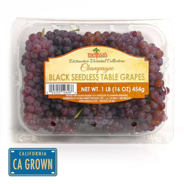 Melissa's Champagne Black Seedless Table Grapes in a clear plastic clamshell container, with a yellow-orange label and a blue 'California Grown' badge at the bottom left.