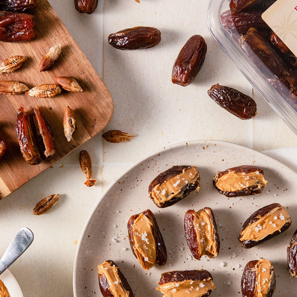 pitted dates on a wood cutting board and a plate of peanutbutter stuffed dates.