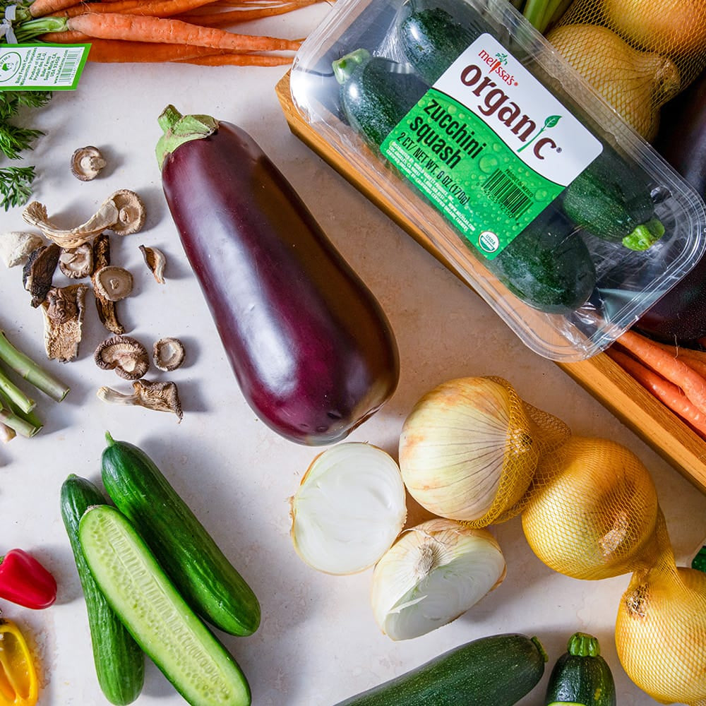 Assorted fresh vegetables including carrots, cucumbers, and bell peppers on a white surface.