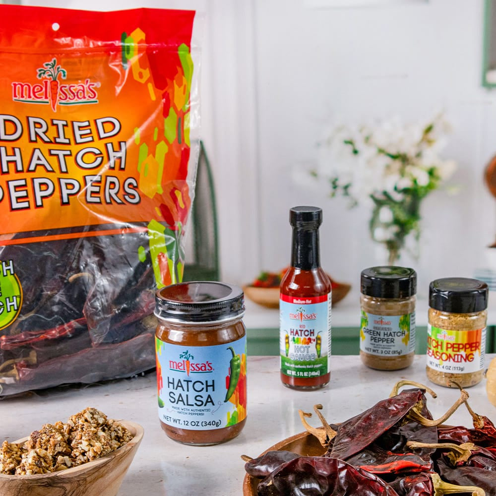 White counter in a kitchne with dried hatch peppers , hatch salsa, clean snax, hatch pepper seasoning, and hatch pepper polenta.