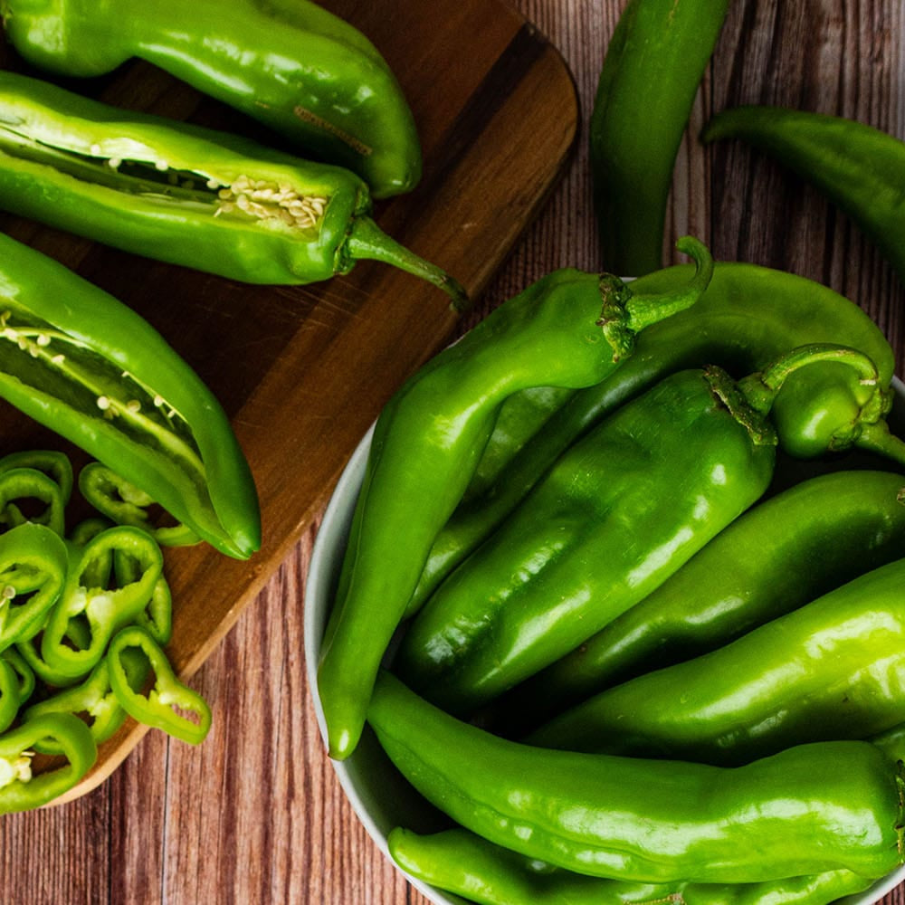Hatch peppers on a wooden cutting board and table